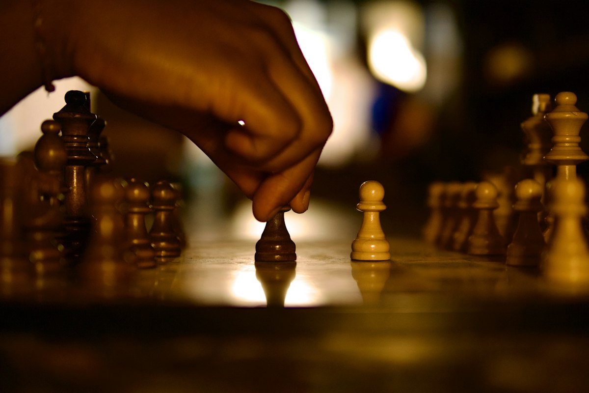 A hand placing a chess pawn on a softly lit board